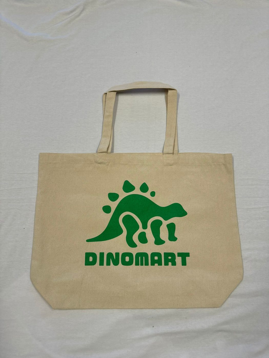 Canvas tote bag with a green screen printed Dinomart logo by Ray's Print